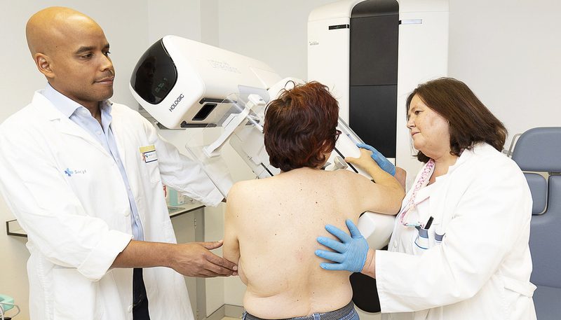 Dos profesionales sanitarios atienden a una paciente en un mamógrafo