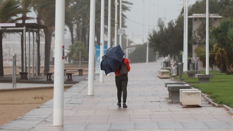 Un viandante en el paseo marítimo de Gandía durante una tormenta